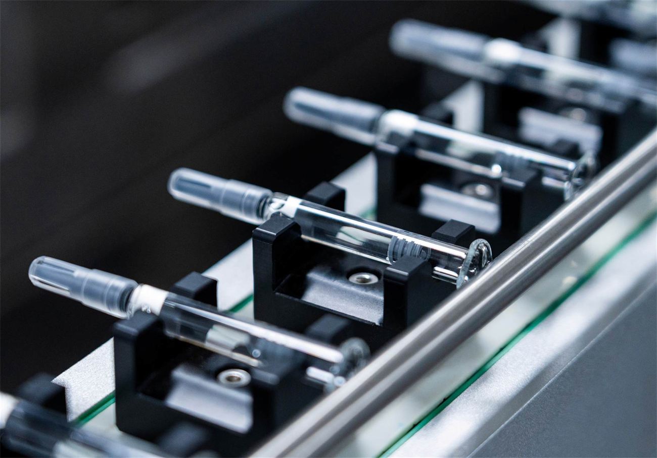 Pre-filled syringes held in a filling-line rack inside Hyteka's Class A GMP aseptic environment